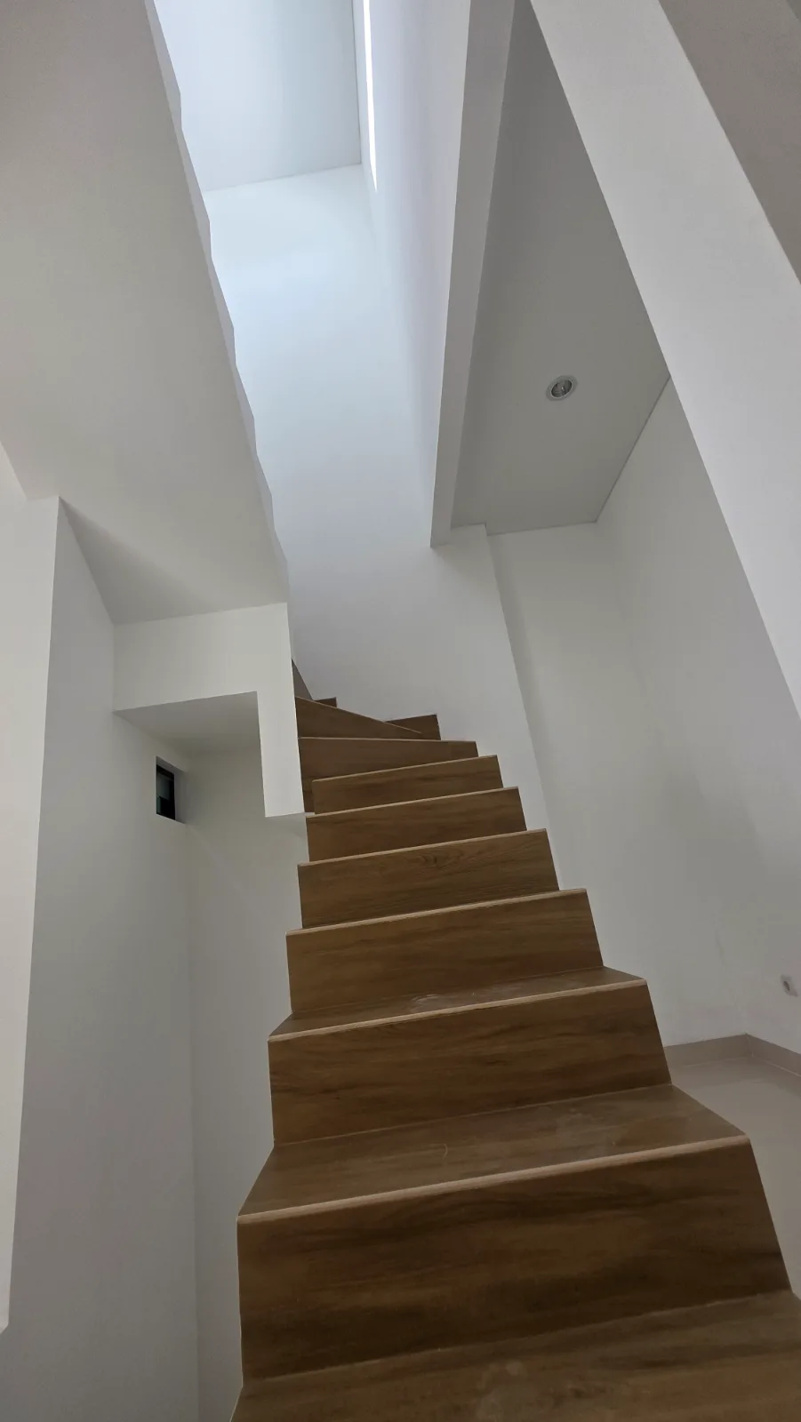 Tangga dengan finishing motif kayu yang hangat menghubungkan antar-lantai.